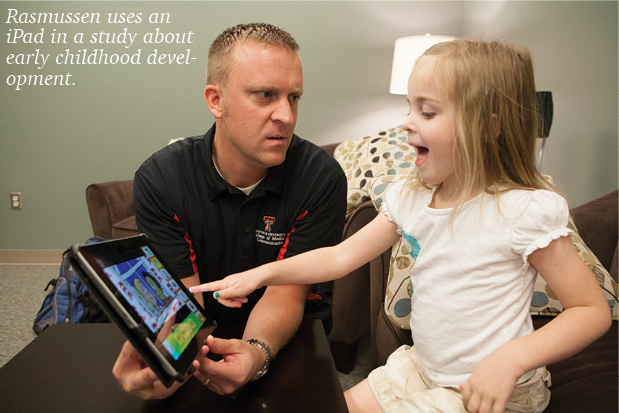 Dr. Rasmussen giving a child an iPad to play with