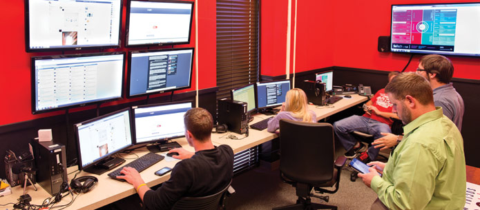 Students and faculty member Trent Seltzer, Ph.D., monitor social media in the Outpost