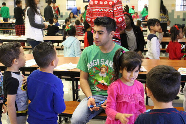 Ryan talks to kindergarten students at a financially-disadvantaged elementary school during the Christmas party hosted by Charitable Crusaders.