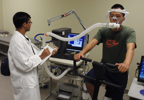 Kinesiology & Sport Management Cardiorespiratory Lab with doctor looking at computer and patient riding bike with respiratory equipment