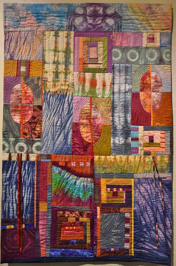 art quilt with vertical orientation and space divided with geometric images and quilt blocks