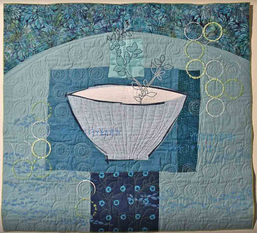 square art quilt in blues with small bowl in center