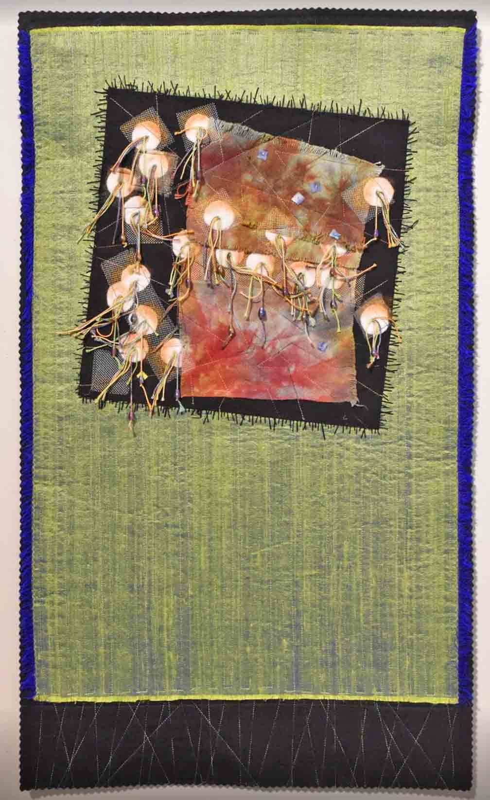 Vertically oriented art quilt with green background and embellished square