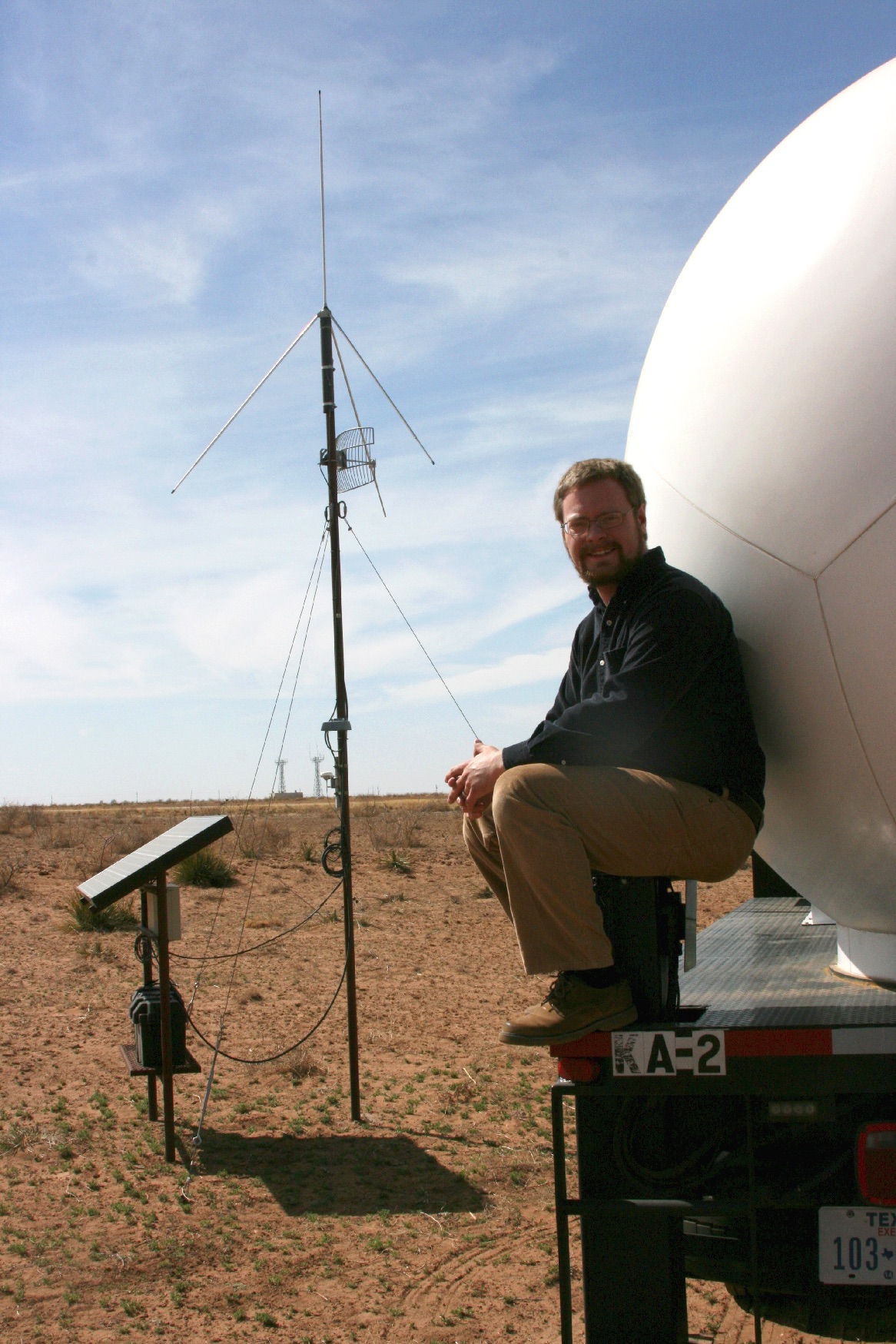 Dr. Eric Bruning poses in the field beside a ka-band truck.