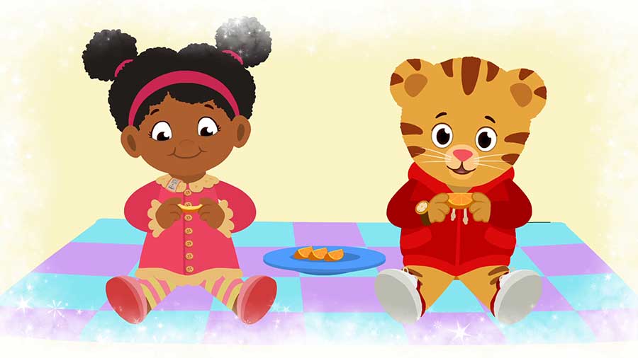 daniel tiger and girl sitting on blanket, trying oranges