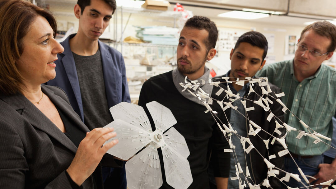 Maria Perbellini holding a 3-dimensional model as she instructs graduate students in the College of Architecture.