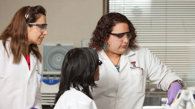 Three female researchers inspecting something in the lab.