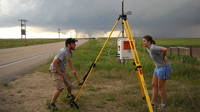students setting up StickNet with tornado in the background