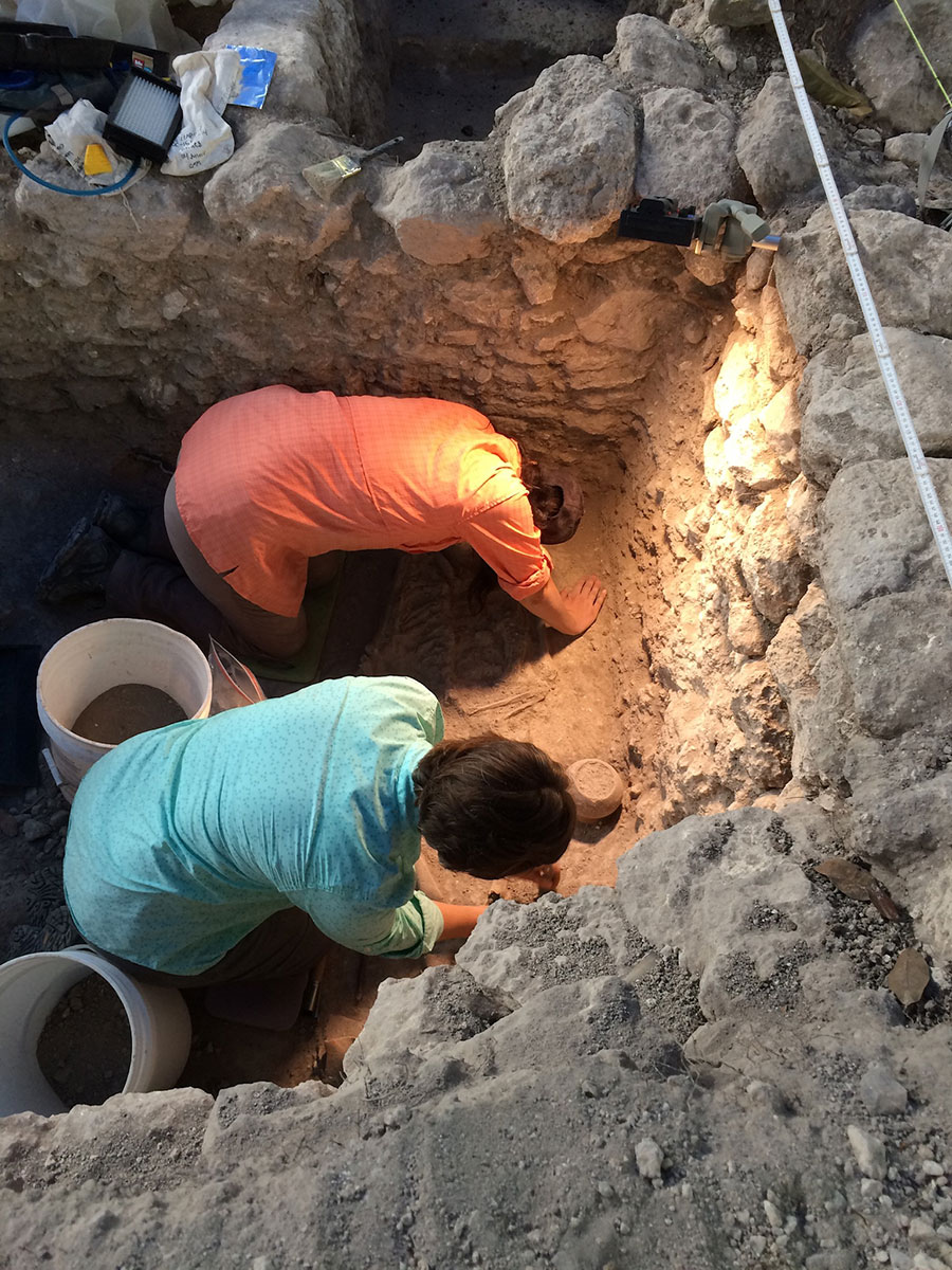 two women in pit, excavating artifacts