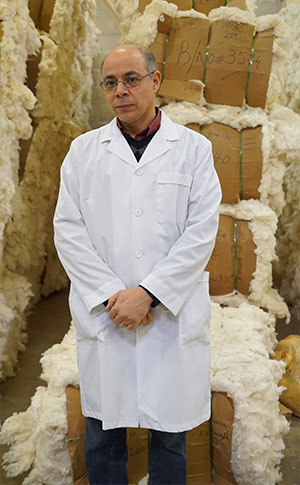 abidi stands in front of bales of cotton