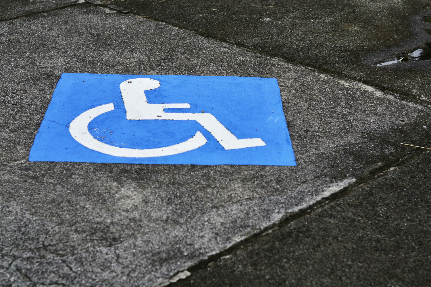 Blue handicap icon painted on asphalt parking spot.