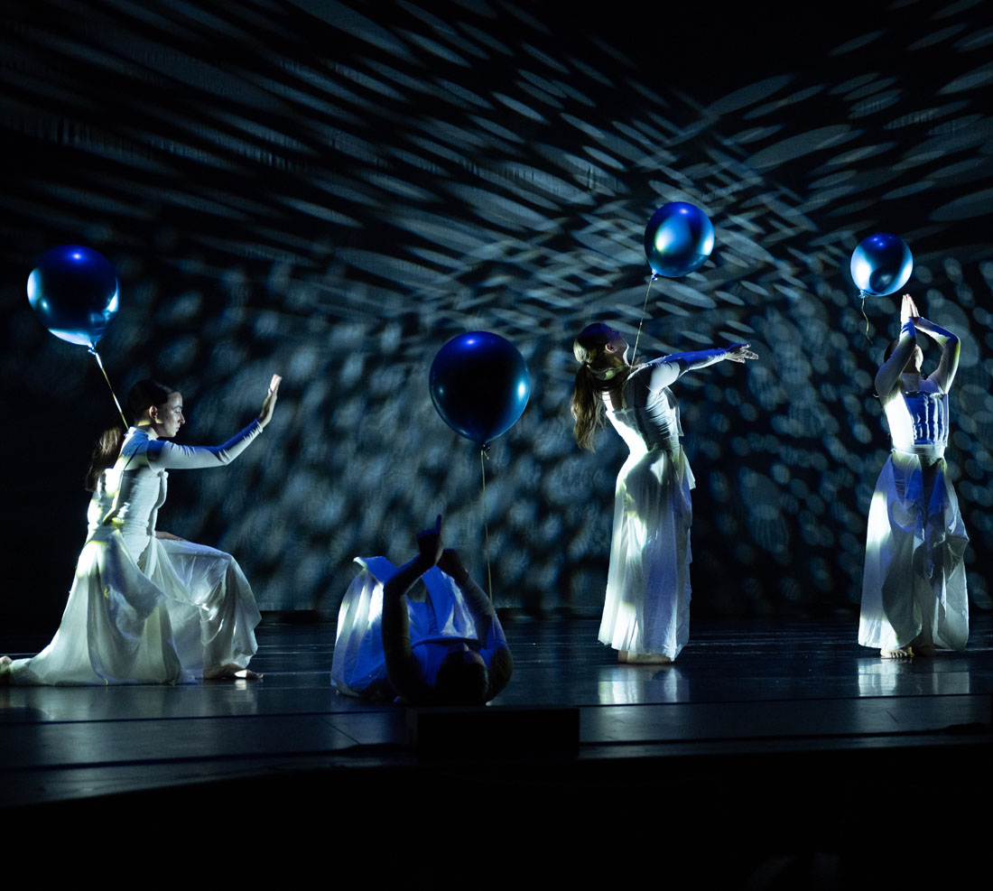 TTU Dance students performing on stage with dark blue lights in the background