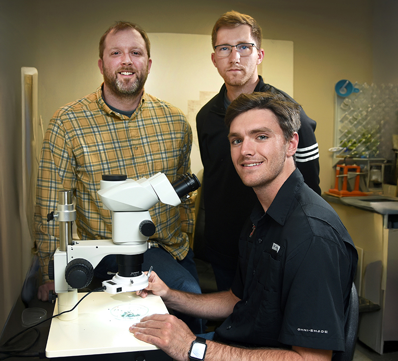 Three persons with a microscope