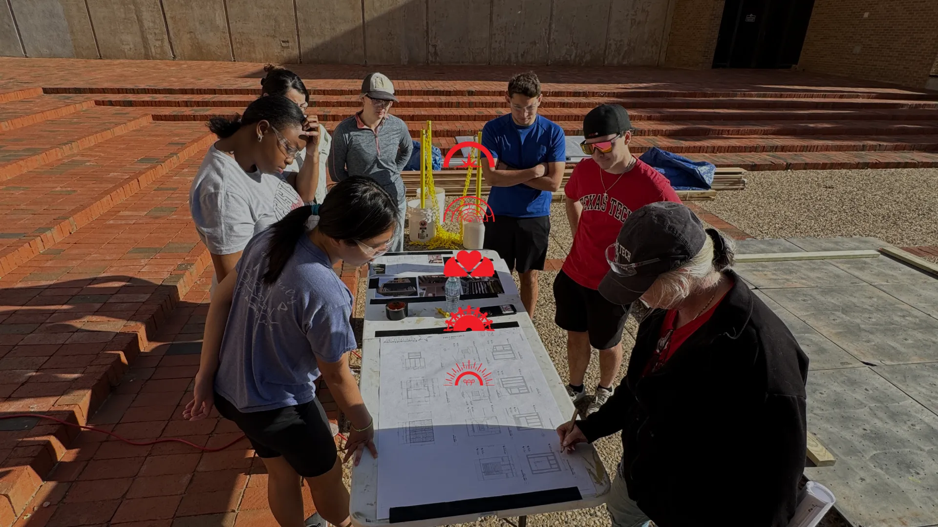 Students working outside studying building plans for a project.