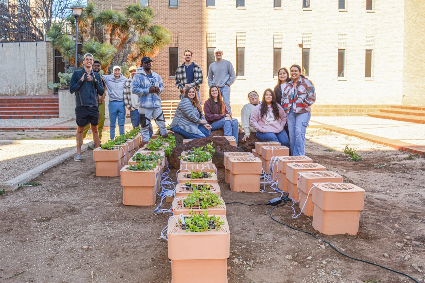 Students sitting in an outdoor courtyard with 3D printed planters.