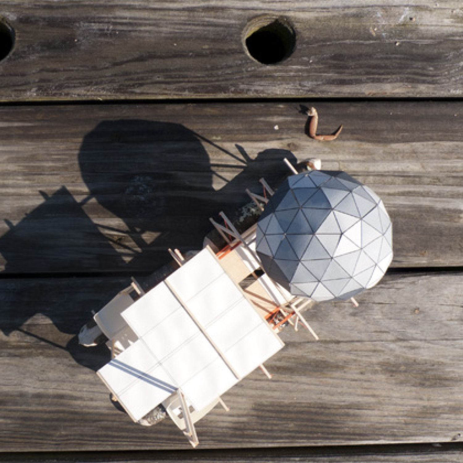 Paper and wood model on a wooden deck.