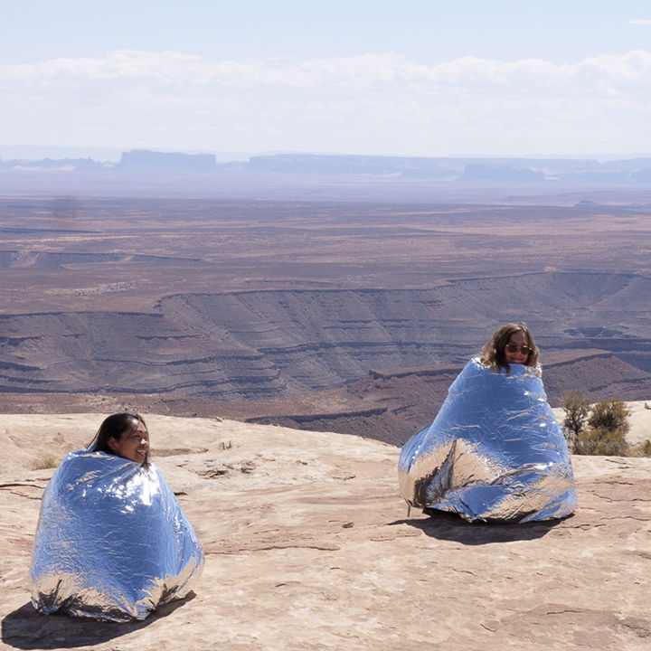 Students in foil blankets on a plateau.