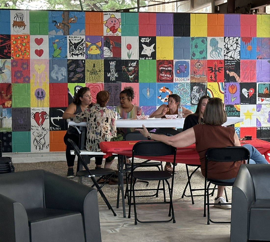 People sitting at a table with a wall of art behind them