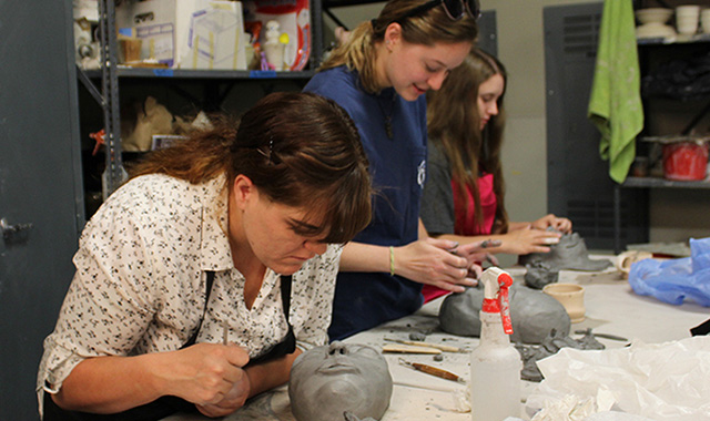 Students and faculty working with clay