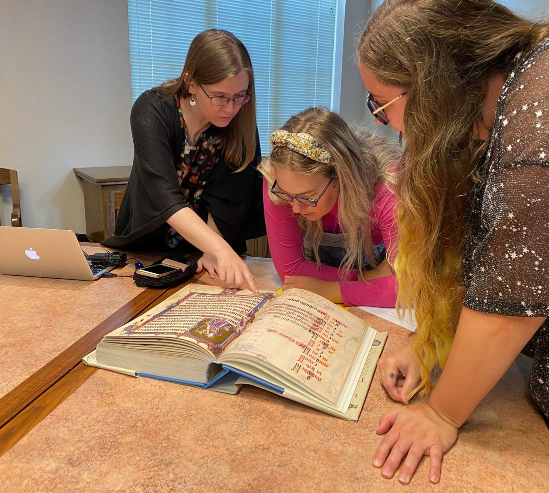 Faculty with students looking at Art History book