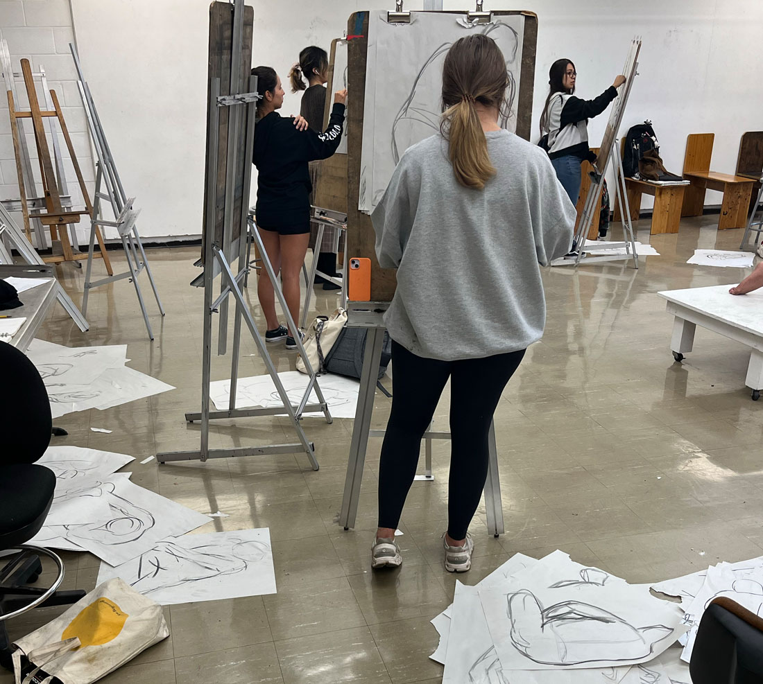 Students drawing in a classroom using an easel