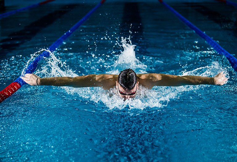 man swimming in olympic pool