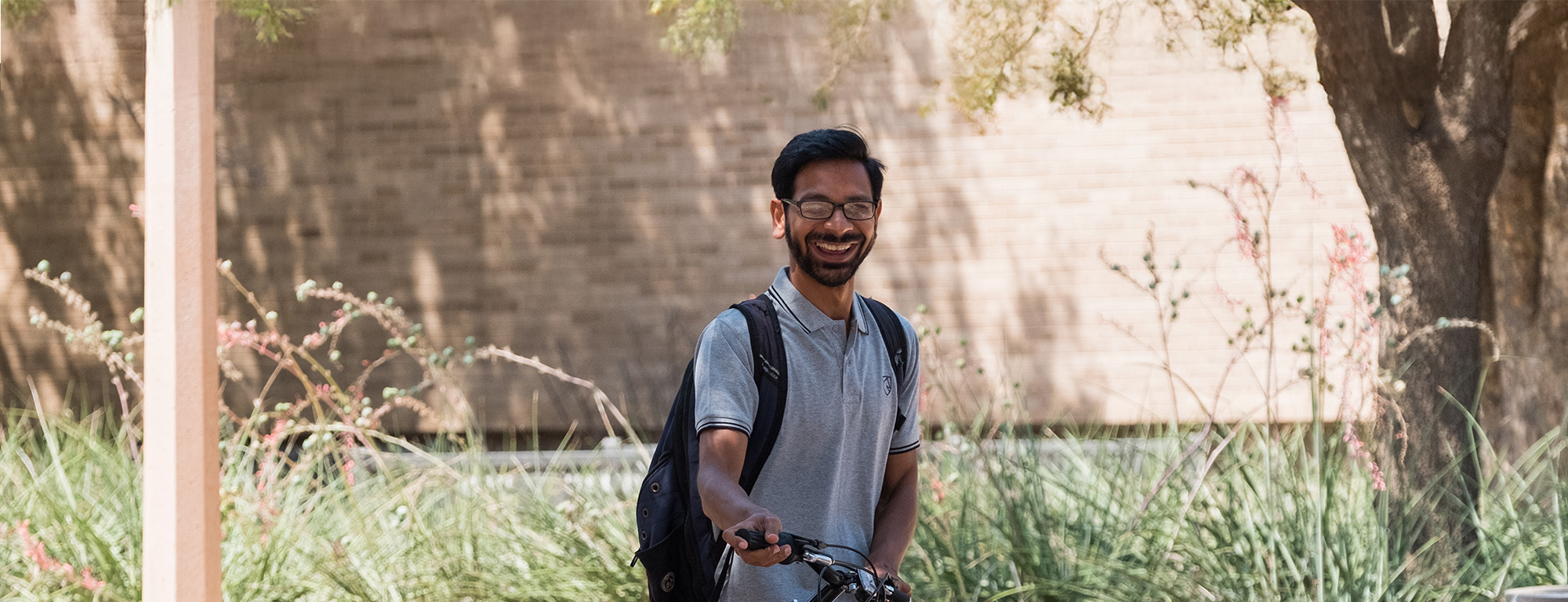 Texas Tech student holding a bike and smiling