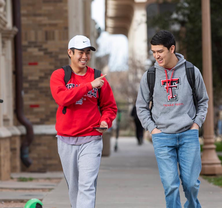 two texas tech university students walking outside on campus grounds