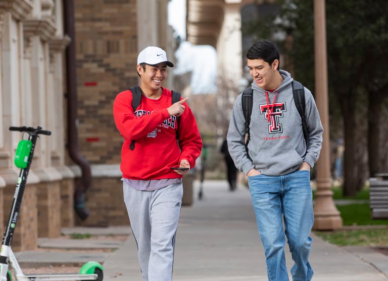 two texas tech university students walking outside on campus grounds