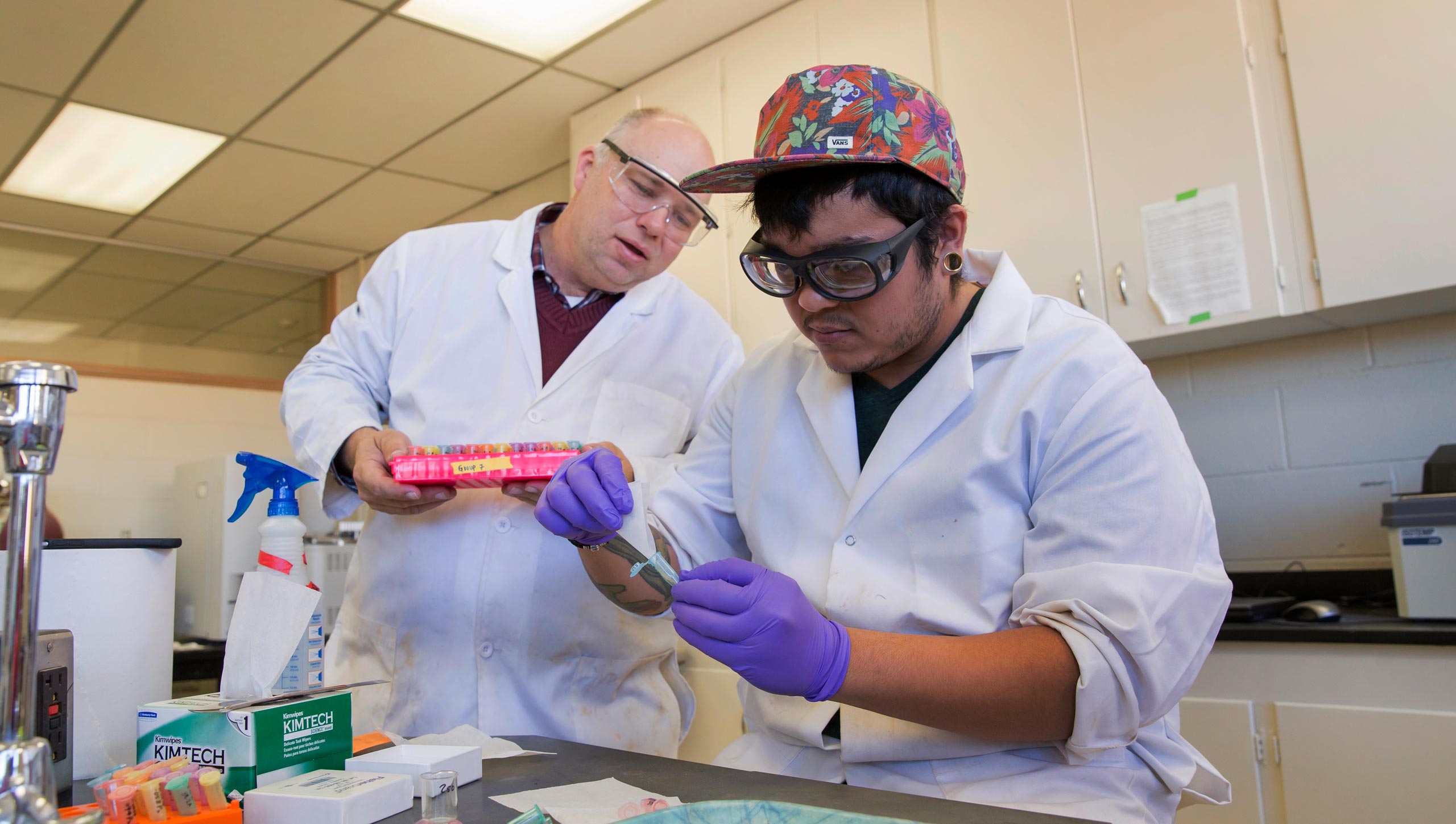 two students in a chemisty lab analysing a pair of vials