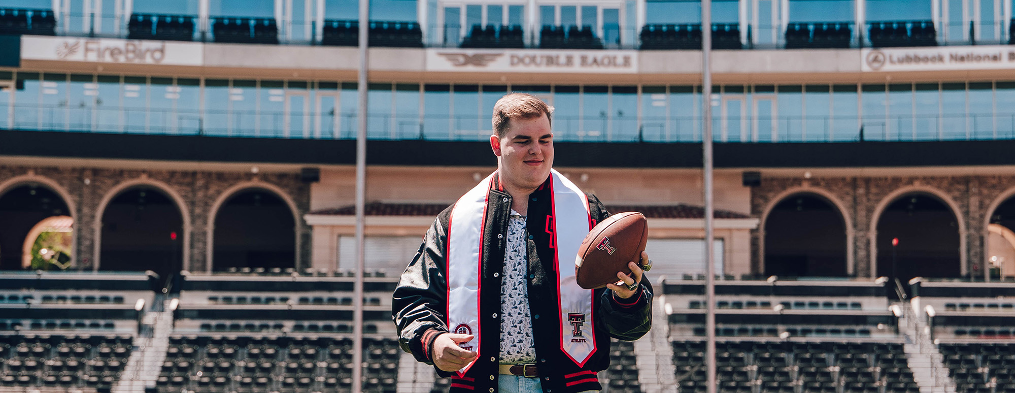 Graduation photo of Jurrien Loftin on the football field holding a football