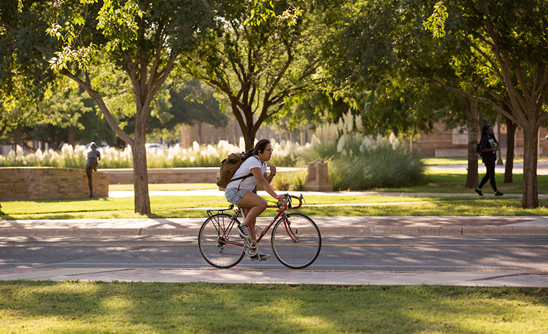 woman riding a bike through texas tech campus
