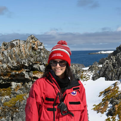 dr. van gestel in antartica with coastline behind her