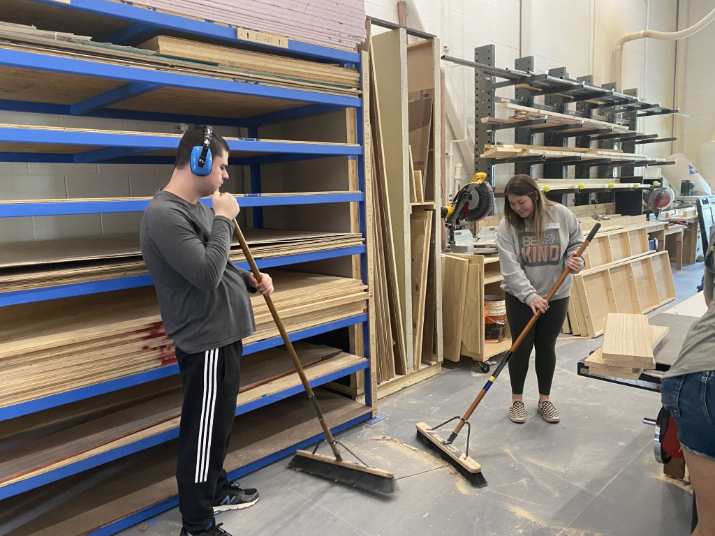 Students sweeping in a woodshop