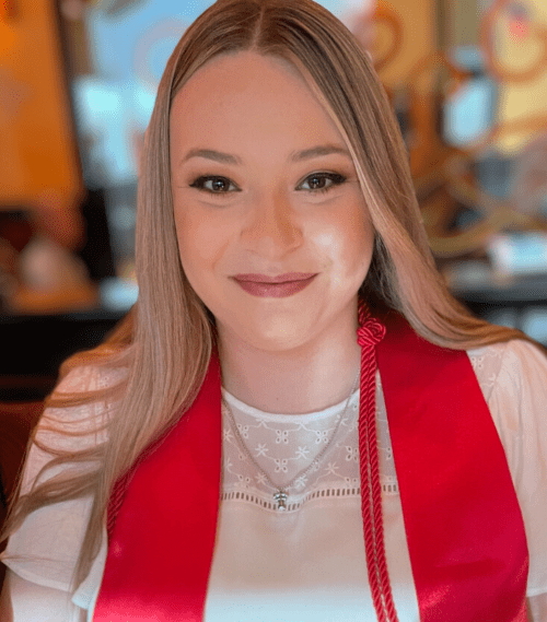 Maddie Motley in a white shirt with red banner and graduation cord