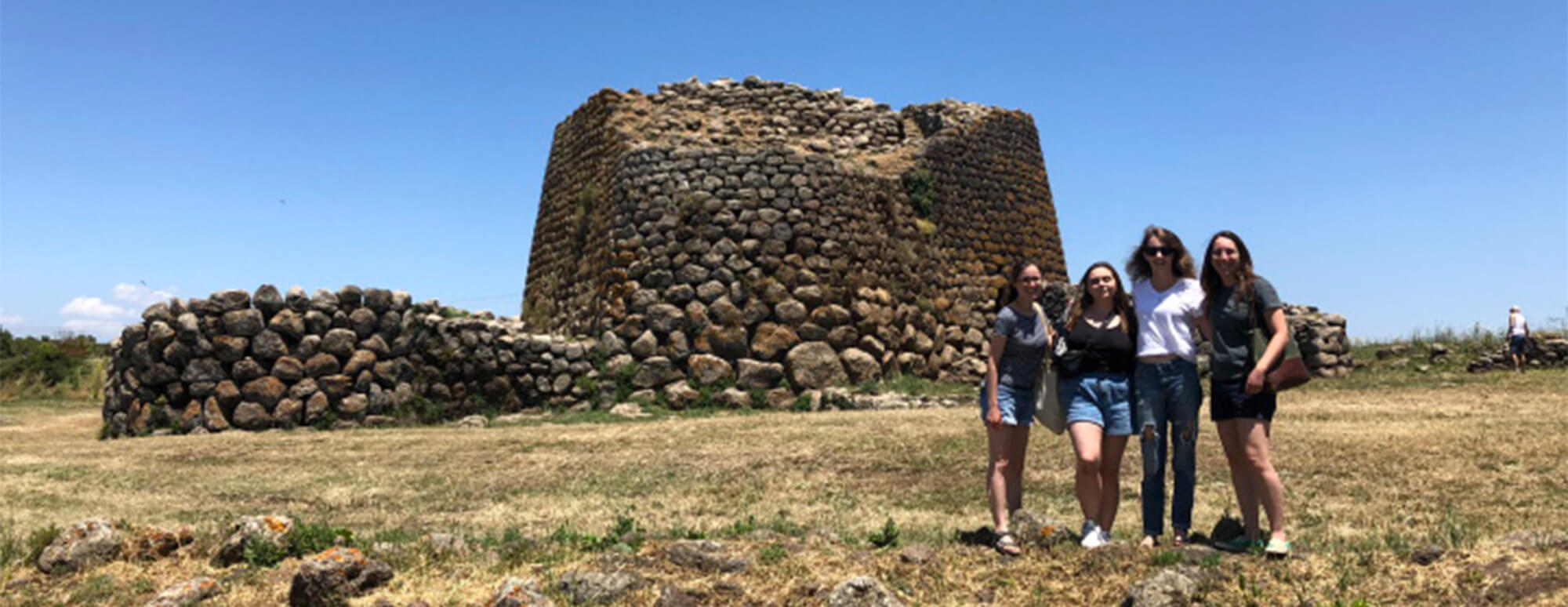 archeology students posing for a picture in front of ruins