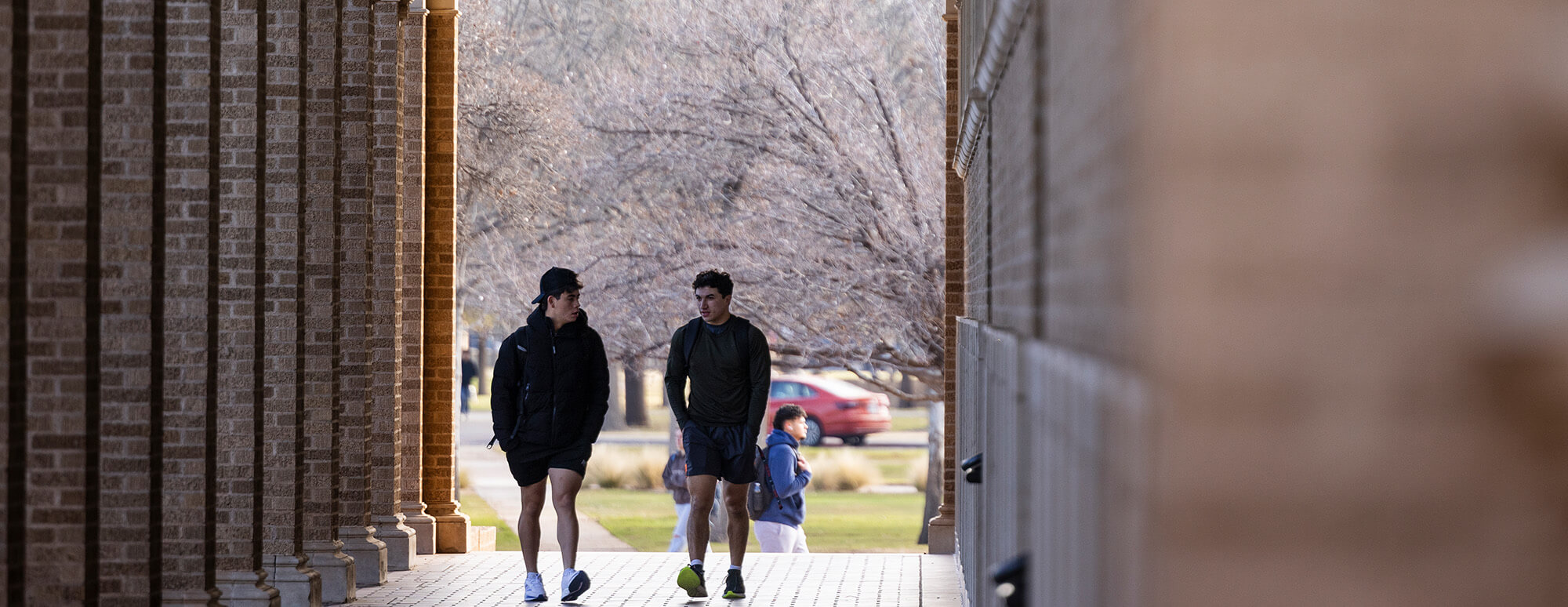 students walking underneath building arches