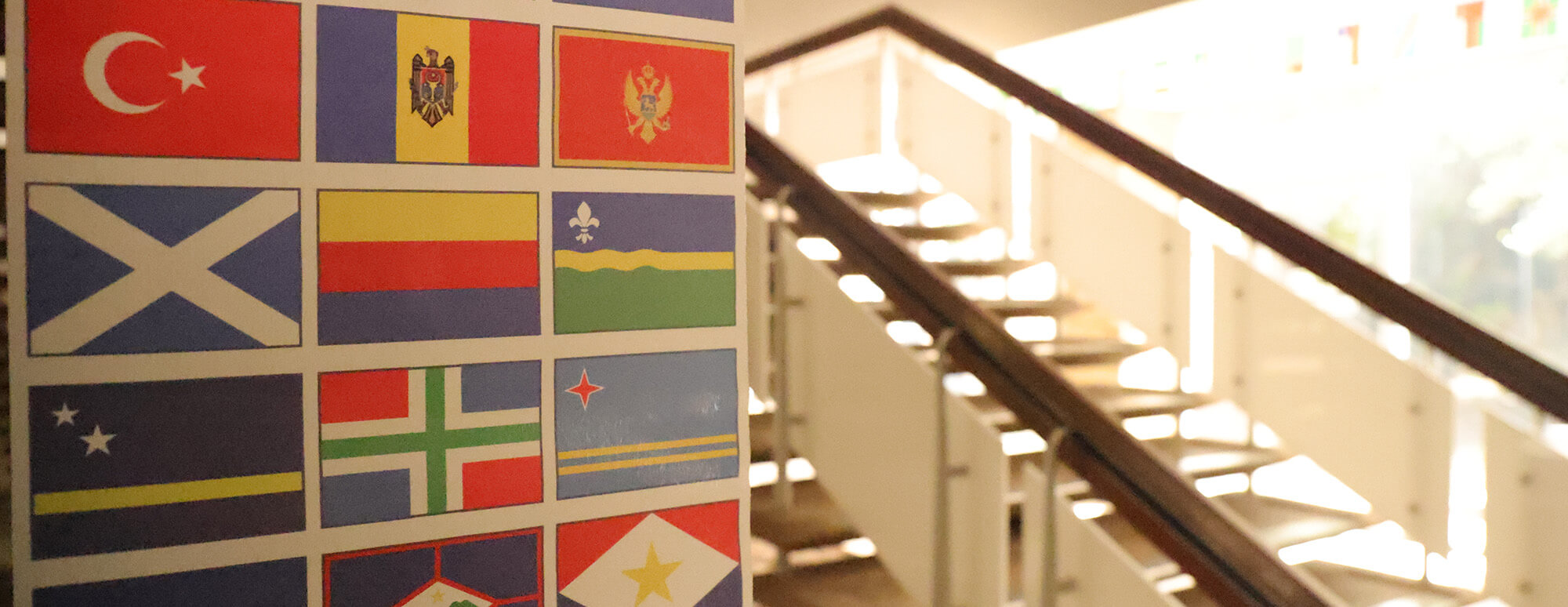 banner with country flags hangs in front of a stairways of the cmll building
