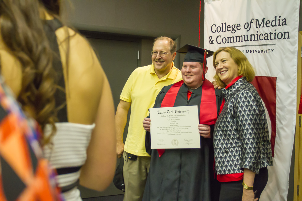 Student taking picture with diploma and parents