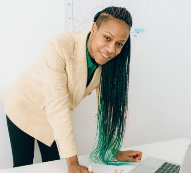 woman leans over a desk and smiles confidently