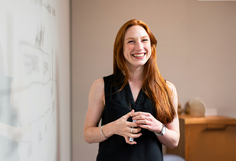 student smiling in front of dry erase board