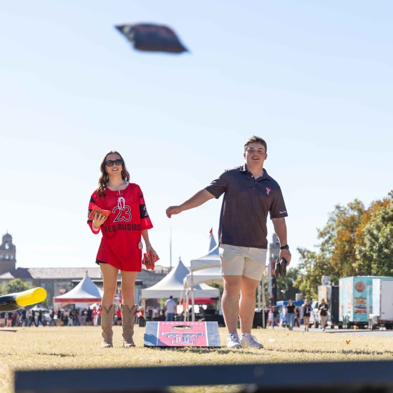 Couple playing a beanbag game at the tailgate