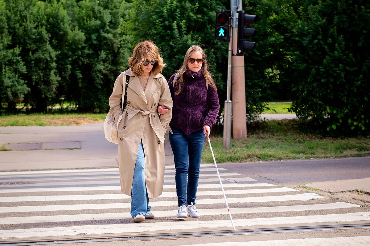 Blind woman and guide cross the street together.