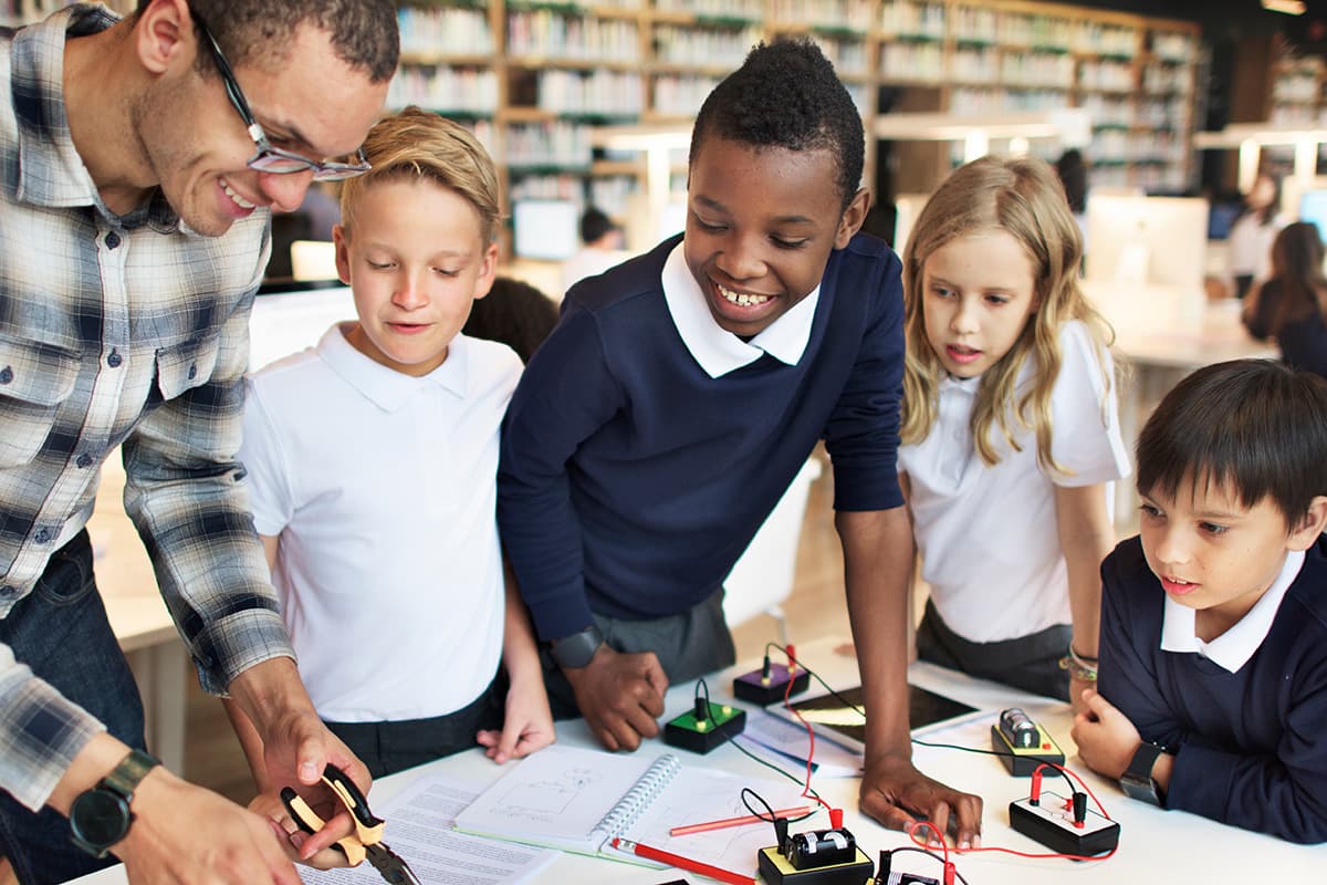 Teacher supervising students working with an electronics kit.