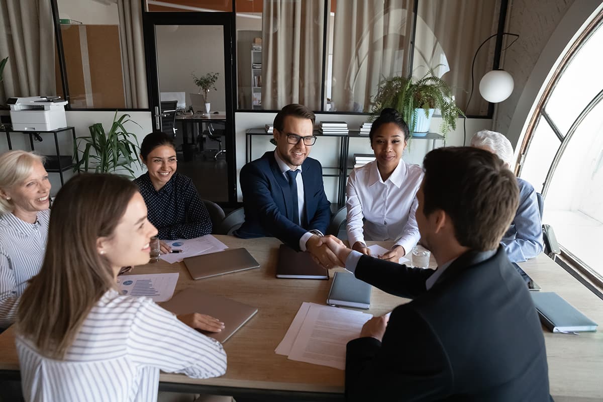 Group of administrators shake hands in a conference room.