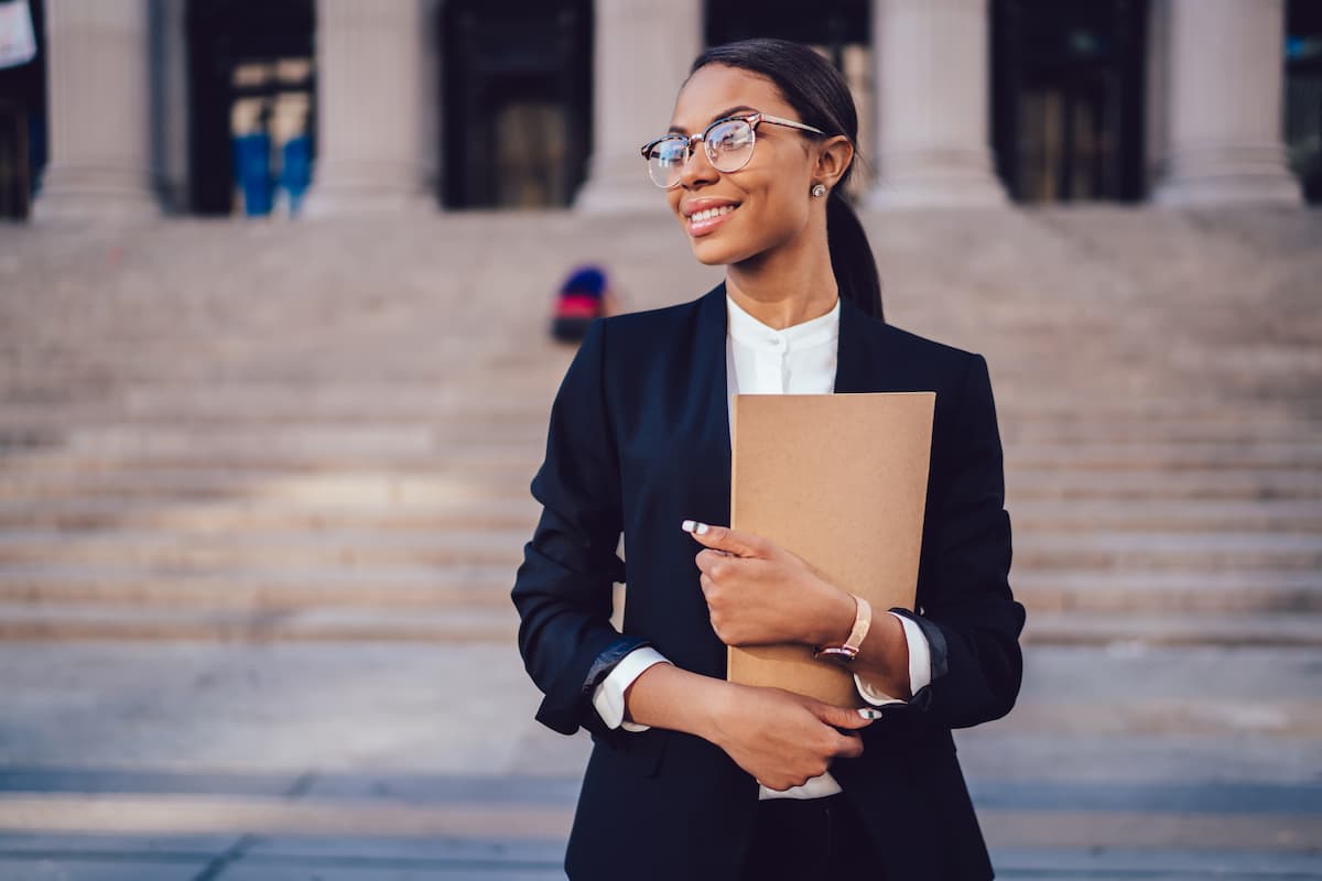 Woman in business attire holding folder at the foot of courthouse steps.