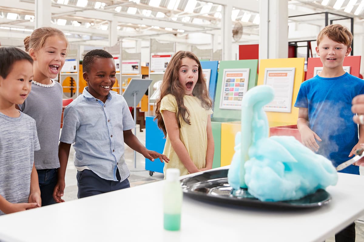 Elementary school students watching a science demonstration producing bubbly blue foam.