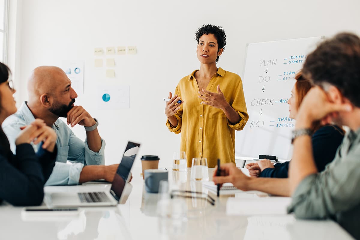 Woman giving presentation in conference room with whiteboard.
