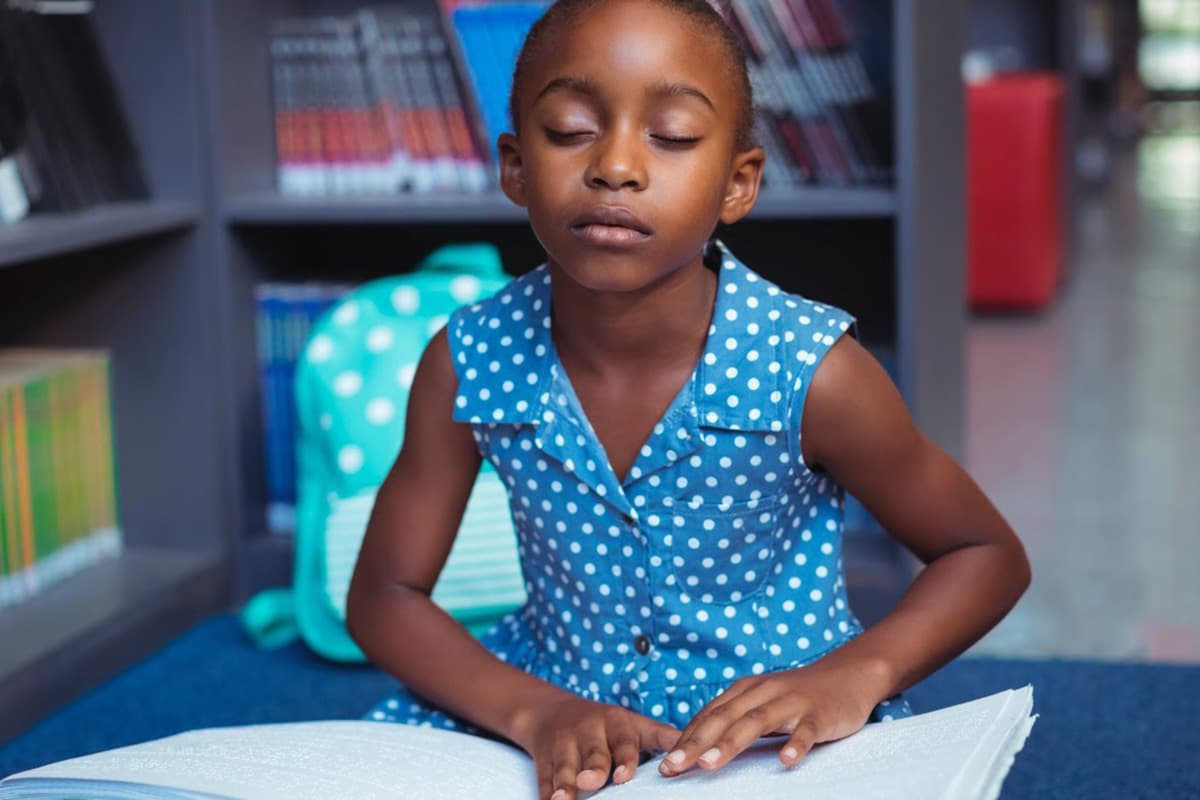 Girl reading Braille book in library