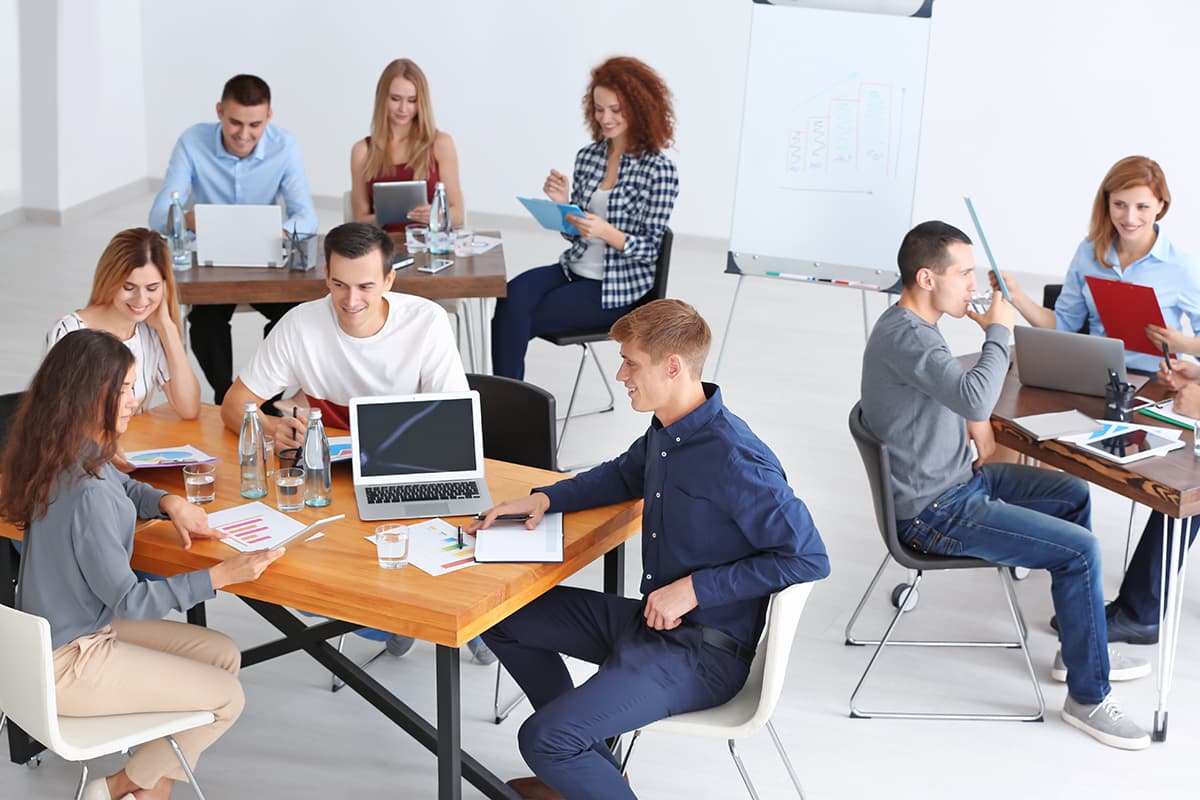 Small groups of students having discussions at separate tables in STEM lab setting.
